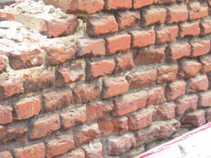 Zbylý kus zdi v místě parapetu se zřetelnými stopami degradace stěny