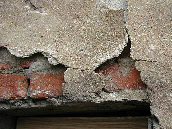 Nejvíce poškození bylo zaznamenáno v exponovaných místech fasády. Detail destrukce renesanční omítky nad hranou špalety okna (stav před konzervací, 2003)