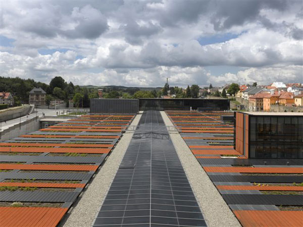 Střecha budovy, na které se střídají pásy betonových truhlíků se zelení a pásy korodujícího plechu Corten