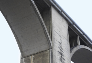 Obr. 10 Oblouky s horní mostovkou. Vlevo: mostovka desková, posuvné uložení mostovky na opěře pomocí železobetonové kyvné stojky s vrubovými klouby na koncích, vzpěry nad obloukem jsou stěnové, vetknuté na horním i dolním konci; Cheb – most u Spáleniště, 1946, L = 25,5 m. Vpravo: posuvné uložení konce mostovky nad patkou oblouku – pružná příčná stěna podpěry je vetknutá do konce mostovky a oddilatovaná svislými spárami od podélných stěn krabicové podpěry, zde dvoukloubový oblouk (je viditelná spára v patě oblouku), mostovka je roštová; Podolsko, 1942, Lmax = 150,0 m.
