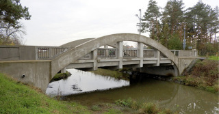 Obr. 06 a Oblouk s dolní mostovkou – nosná konstrukce (oblouk i mostovka) vetknutá do obou podpěr, mostovka bez příčných dilatačních spár. Vlevo: celkový pohled. Vpravo: detail rámového rohu. Křinec-Zábrdovice, 1915, L = 19,020 m.