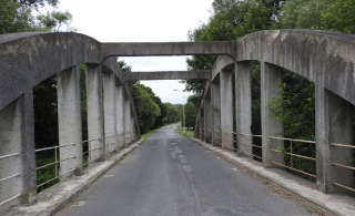 Obr. 10 a Dvoukloubový oblouk s dolní mostovkou, bez chodníků. Vlevo: povrch mostu. Vpravo: podhled mostu – mostovka bez podélných táhel (vodorovná síla z oblouku se přenáší přes klouby přímo do podpěr). Brantice, 1920, L = 32,0 m.